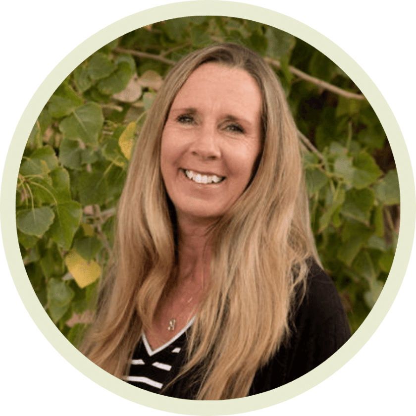Photo of Lynn: tan woman in her 50s with a bright white, toothy smile and long, full blonde hair wearing a striped black and white shirt